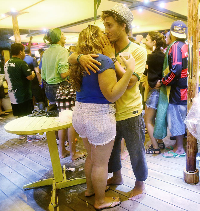 A Brazil fan is embraced by a woman in a bar on Copacabana Beach