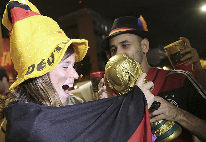Germany soccer fans celebrate with a replica of the World Cup trophy in front of Maracana stadium at the end of the World Cup final on Sunday