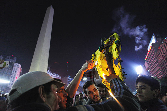 Argentina's fans set fire to a Brazil soccer jersey as they gather around the Obelisk on Sunday