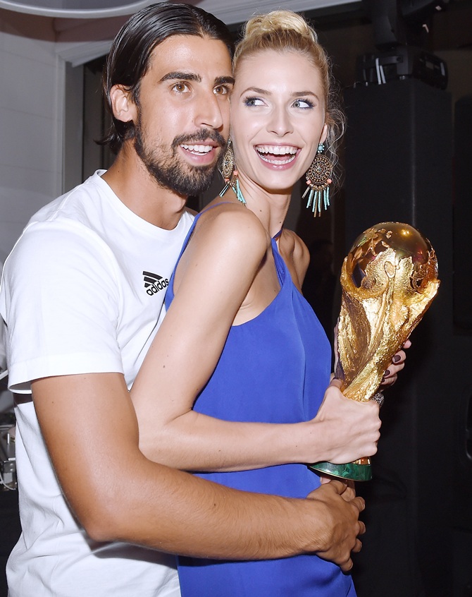 Sami Khedira of Germany and girlfriend Lena Gercke pose with the World Cup trophy as   he celebrates with teammates at a party, after winning the 2014 FIFA World Cup