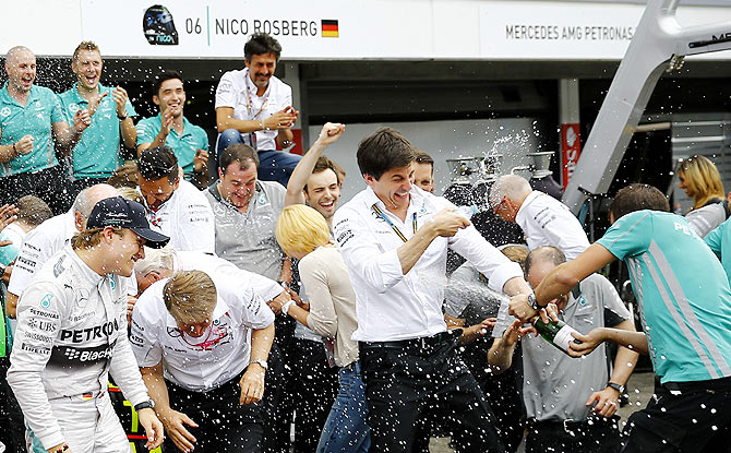 Mercedes Formula One driver Nico Rosberg (left) of Germany and Mercedes motor sport chief Toto Wolf try to evade a champagne shower after the German F1 Grand Prix at the Hockenheim racing circuit on Sunday