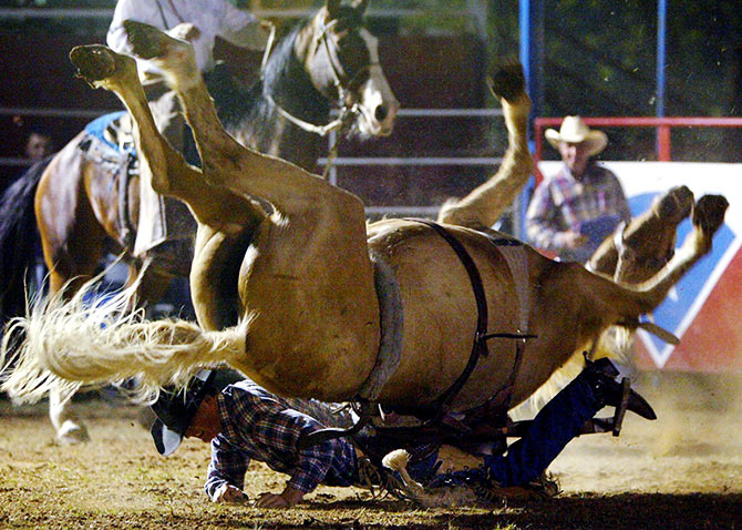 Cowboy Jim Butler is thrown over the head of his bucking horse
