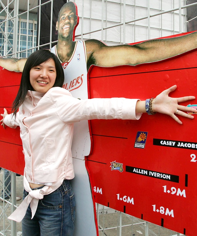 Basketball fan measures her spans against a life-size cutout of National Basketball Association star Lebron James