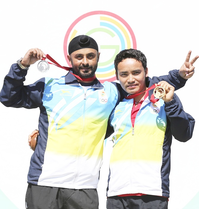 Silver Medalist Gurpal Singh of India and Gold Medalist Jitu Rai of India celebrate on   the podium during Men's 50m Pistol Shooting Final at Barry Buddon Shooting Centre during day five of the Glasgow 2014 Commonwealth Games