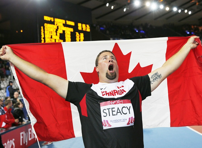 Jim Steacy celebrates with the flag after winning the men's Hammer Throw