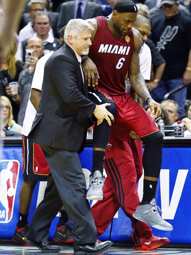 LeBron James of the Miami Heat is helped off the court after cramping up against the San Antonio Spurs