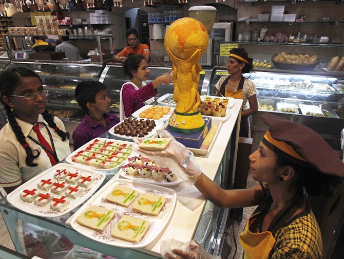 A worker sells sweets next to a replica of the FIFA World Cup trophy, made from sweets in Kolkata