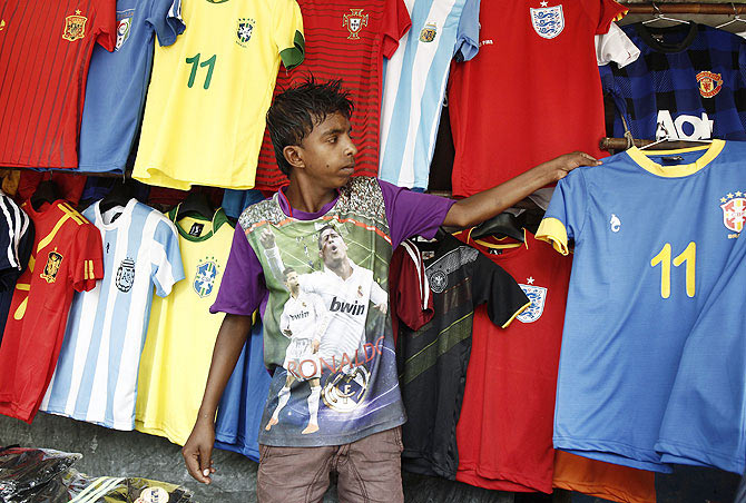 Vendor Mohammad Nihar, 15, arranges World Cup team jerseys at a roadside stall in Kolkata