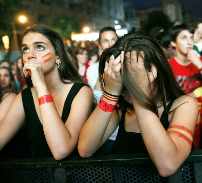 Spain supporters react as they watch the team's 2014 World Cup Group B match against Netherlands on a giant screen