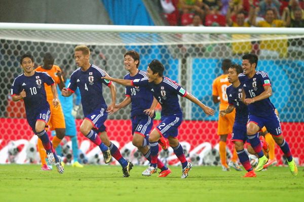 Keisuke Honda of Japan (No 4) celebrates scoring the team's first goal with teammates