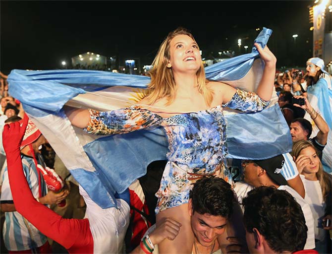 Argentine soccer fans cheer as they watch their team play against Bosnia and Herzegovina on a giant screen