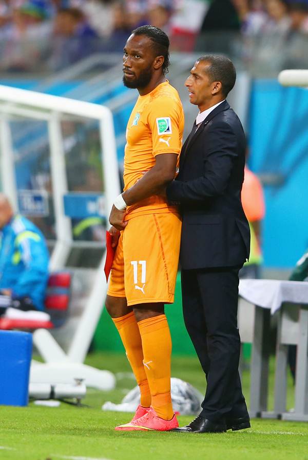Didier Drogba stands on the sidelines with head coach Sabri Lamouchi during the World Cup Group C against Japan.