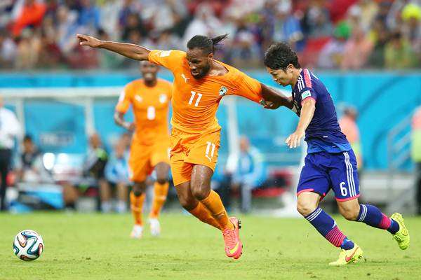 Didier Drogba holds off a challenge by Masato Morishige of Japan