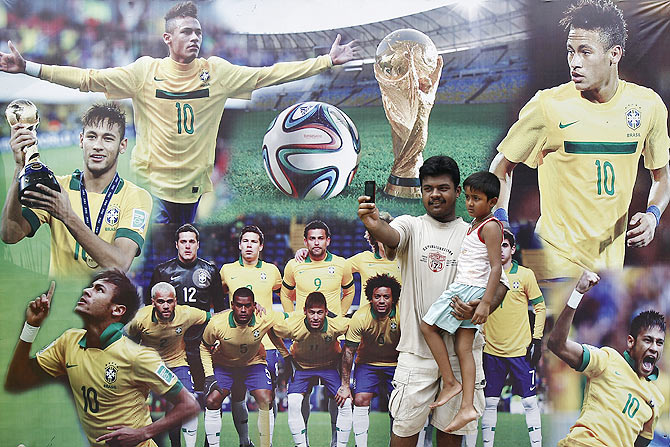 A man takes a selfie with a child, in front of pictures of Brazilian soccer players