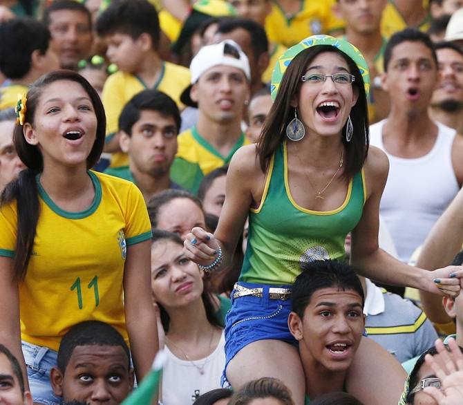 Brazilian soccer fans react while watching the opening match between Brazil and Croatia in a fan zone