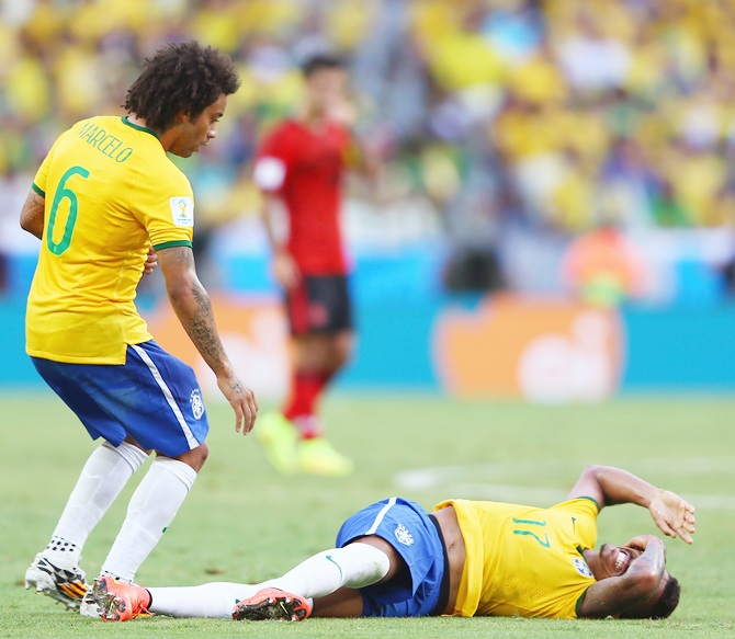 Luiz Gustavo of Brazil lies on the field as Marcelo stands over