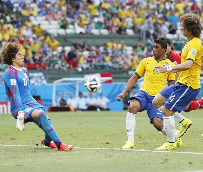 Guillermo Ochoa, left, makes a save in front of Brazil's Paulinho and David Luiz