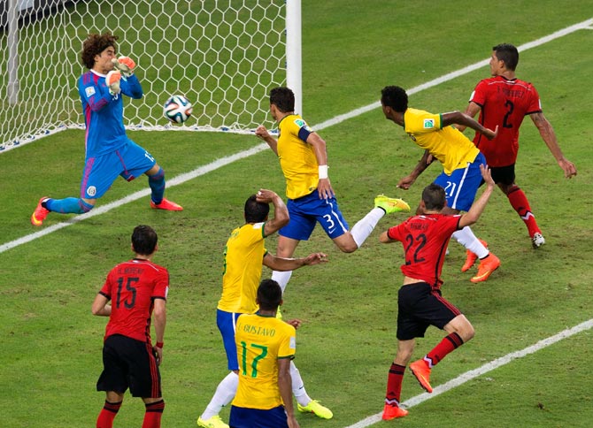Guillermo Ochoa of Mexico makes a save after a header by Thiago Silva of Brazil