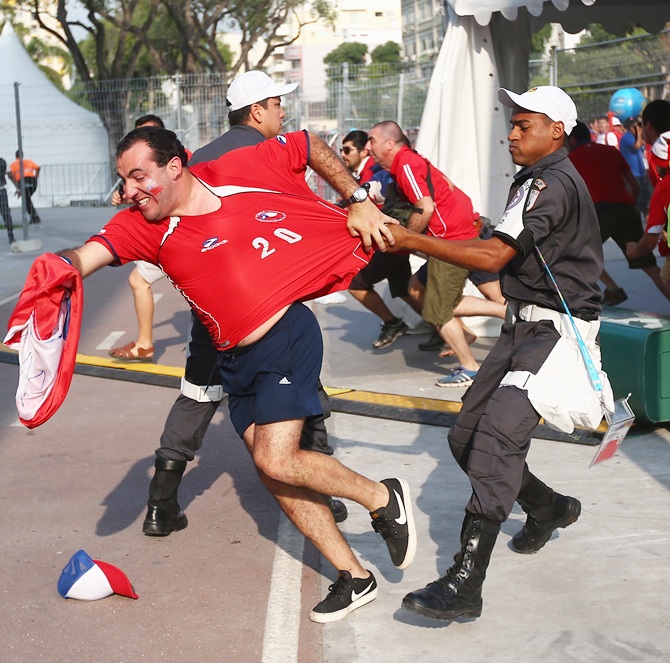 Security personnel attempt to control Chilean fans outside the stadium
