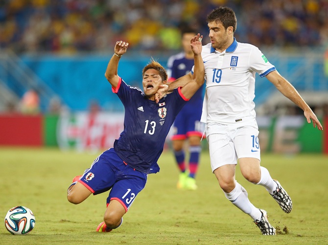 Yoshito Okubo of Japan is challenged by Sokratis Papastathopoulos of Greece