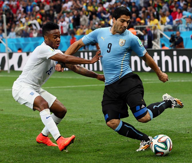 Luis Suarez, right, tries to get the ball past Raheem Sterling of England
