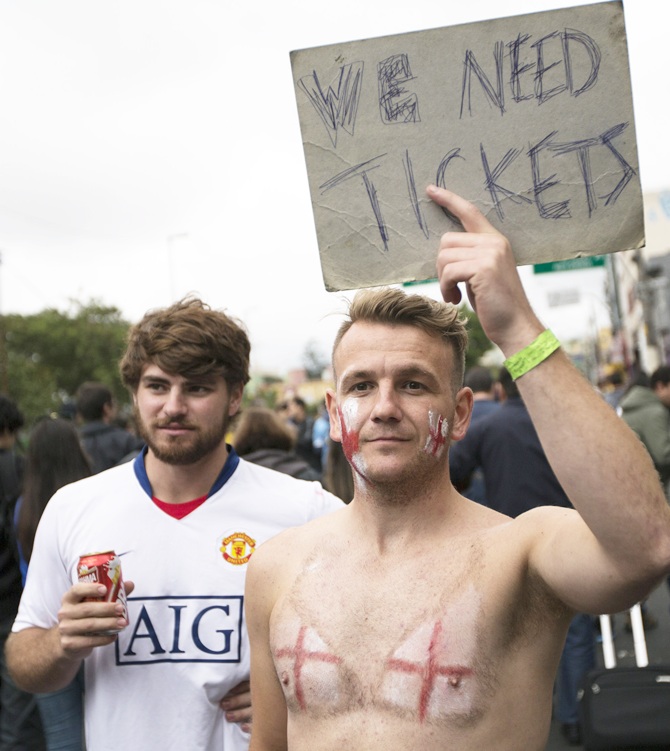 Fans of the England football team hold a sign requesting tickets
