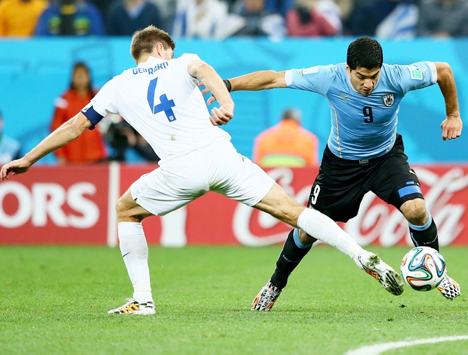 Steven Gerrard of England and Luis Suarez of Uruguay compete for the ball