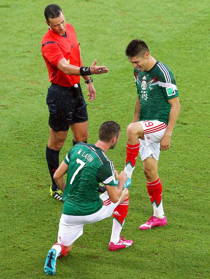 Oribe Peralta of Mexico (R) celebrates his goal with teammate Miguel Layun as referee Wilmar Roldan gestures