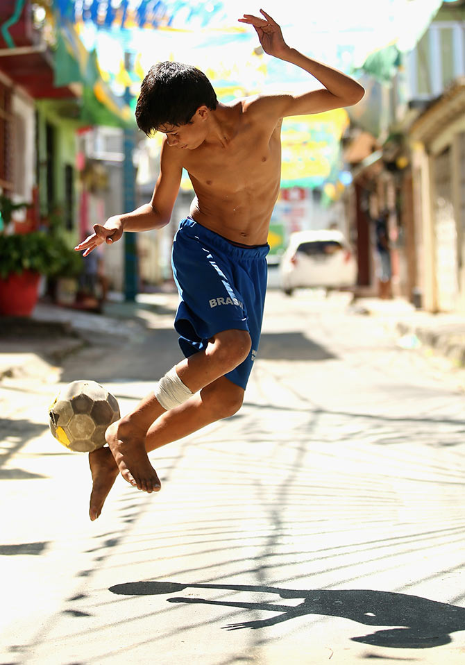 A young boy plays football on the streets in Manaus, Brazil.