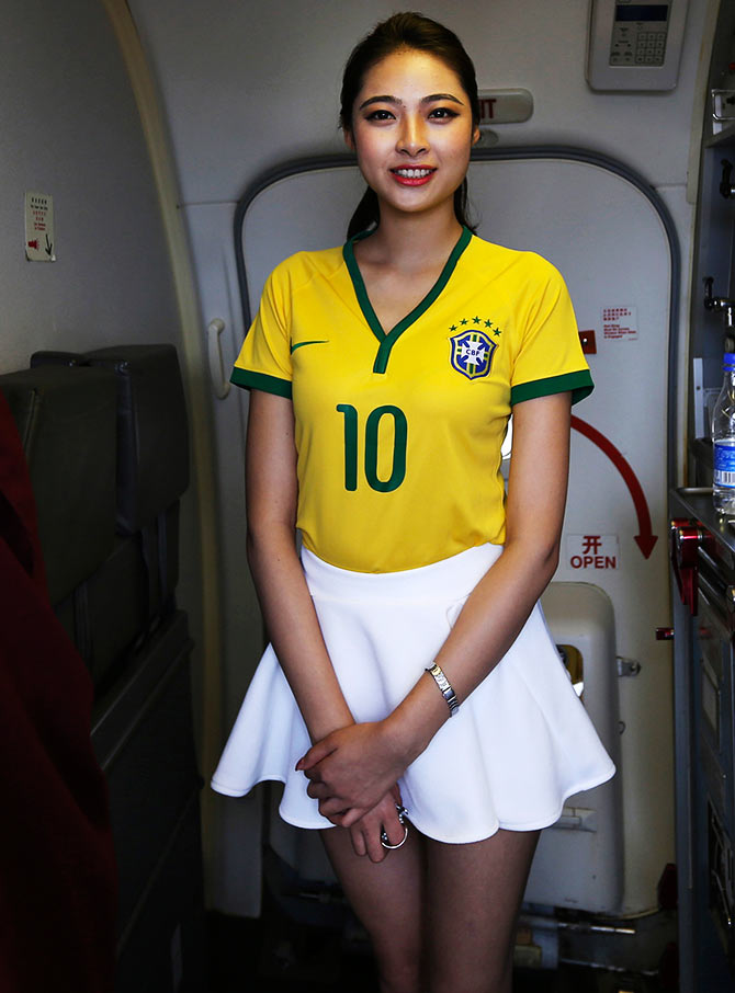 A flight attendant wearing a Brazil soccer team jersey welcomes passengers