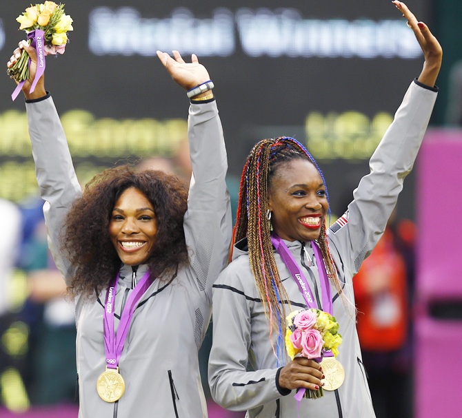 Serena Williams,left, and her sister Venus Williams, of the US, wave with their gold medals during the presentation ceremony for the women's doubles tennis at the All England Lawn Tennis Club during the London 2012 Olympic Games
