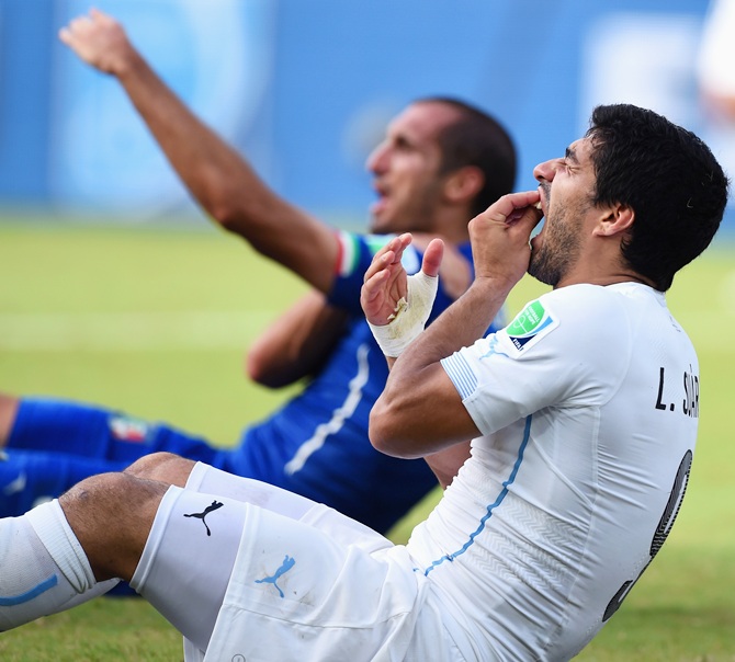 Luis Suarez reacts as Giorgio Chiellini indicates to the referee that he was bitten