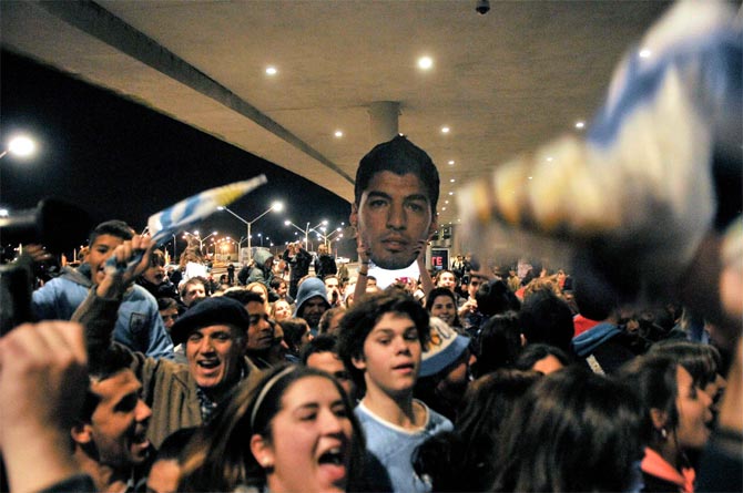 Uruguay's fans gather to express solidarity with player Luis Suarez while they await his arrival outside Montevideo's Carrasco international airport