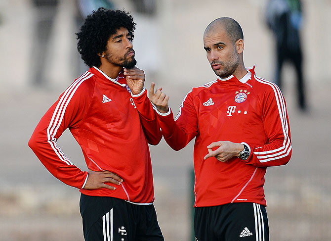 Head coach Josep Guardiola speaks to Dante during a Bayern Munich training session