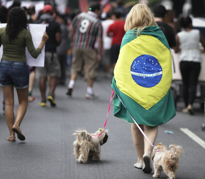 A woman walks her dogs during a protest on the streets near the Maracana stadium in Rio de Janeiro