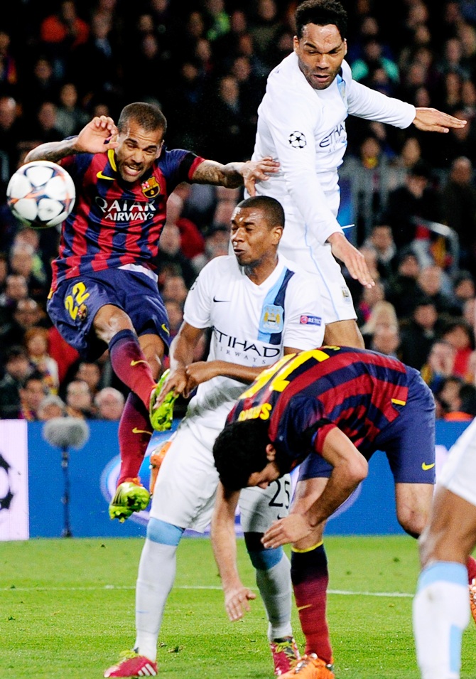 Joleon Lescott of Manchester City rises above Daniel Alves of Barcelona to head the ball