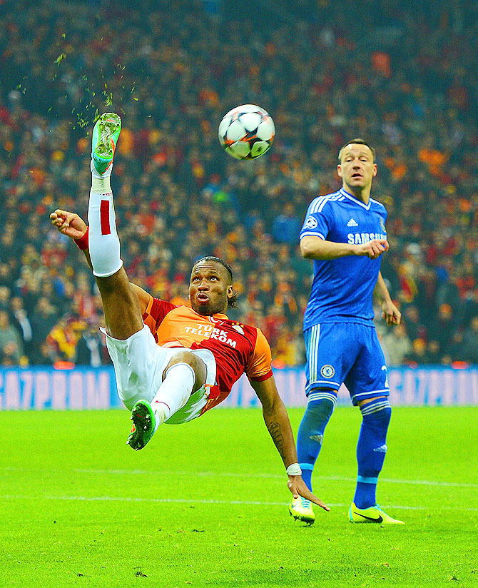 John Terry of Chelsea looks on as Didier Drogba of Galatasaray clears the ball