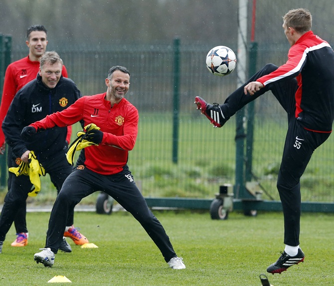 From left, Manchester United's Robin Van Persie, manager David Moyes and Ryan Giggs laugh as Darren Fletcher jumps for the ball during a training session