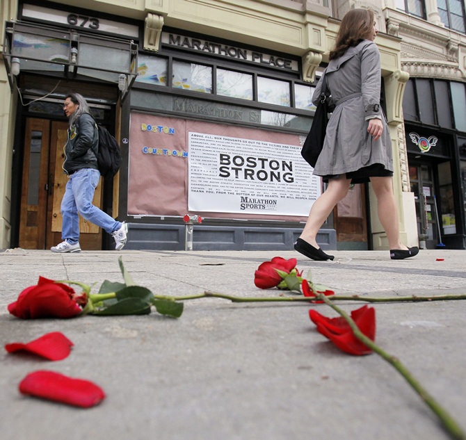 Flowers lie on the sidewalk at the site of the first explosion as people walk along Boylston   Street after the street reopened to the public for the first time since the Boston Marathon bombings in Boston