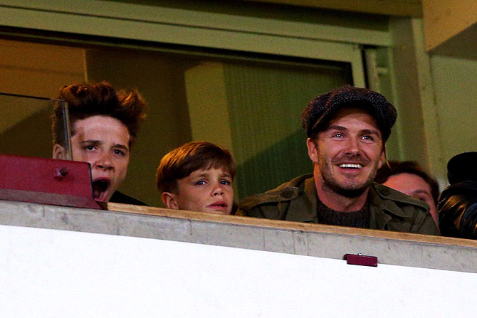 Former England and Manchester United player David Beckham and his sons Romeo and Brooklyn watch the action between West Ham United and Manchester United at Boleyn Ground in London on Saturday