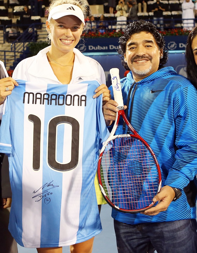 Caroline Wozniacki of Denmark exchanges gifts with football legend Diego Maradona