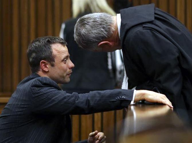 Oscar Pistorius (left) cries as he chats to his lawyer Barry Roux during his trial