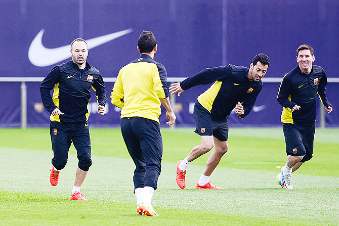 Barcelona's Andres Iniesta, Sergio Busquets and Lionel Messi warm up during a training session on Monday