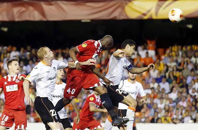 Sevilla's Stephane Mbia (centre) heads the ball to score past Jeremy Mathieu (2nd from left) and Ricardo Costa (right) of Valencia during their Europa League semi-final second leg match at Mestalla stadium in Valencia, on Thursday