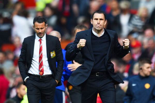 Sunderland manager Gustavo Poyet celebrates his team's 1-0 victory as a dejected Ryan Giggs, Manchester United's interim manager, walks behind.