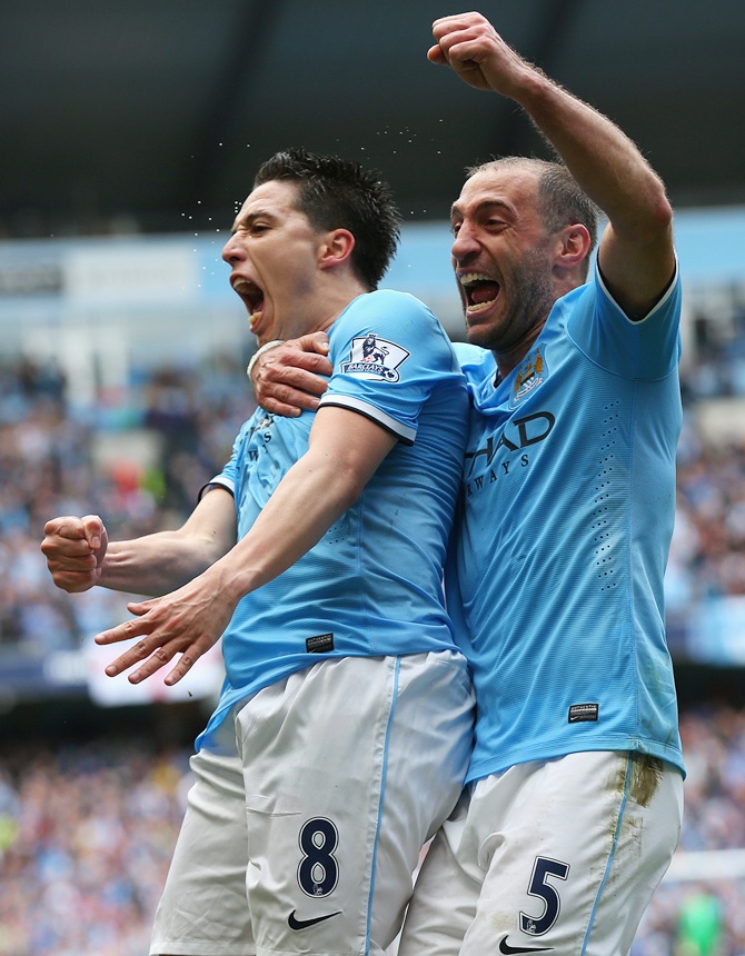 Samir Nasri of Manchester City celebrates scoring the first goal with  team-mate Pablo Zabaleta,right