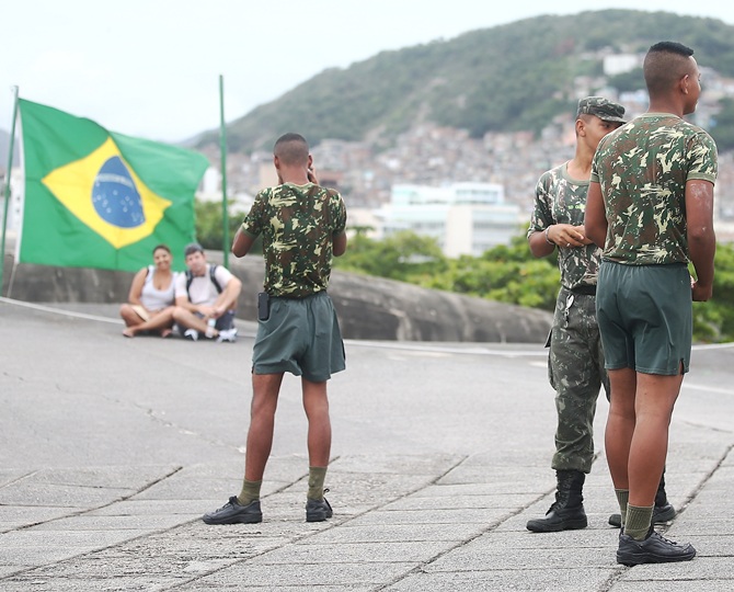 Brazilian Army soldiers stand at Fort Copacabana while visitors pose for a photo