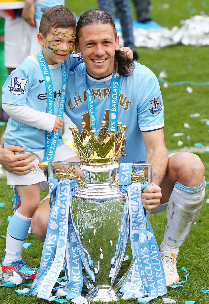 Martin Demichelis of Manchester City poses with the trophy and his son