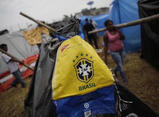A bag with the logo of the Brazilian Soccer Confederation (CBF) is seen on   a newly built shack of a member of Brazil's Homeless Workers' Movement (MTST)   as people carry logs to build their own shacks at the 'People's World Cup' camp