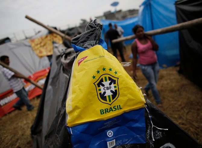 A bag with the logo of the Brazilian Soccer Confederation (CBF) is seen on a newly built shack of a member of Brazil's Homeless Workers' Movement (MTST) as people carry logs to build their own shacks at the 'People's World Cup' camp